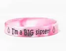 A pink rubber bracelet with the words " i 'm a big sister ".