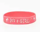 A pink bracelet with the words " it's a girl !" written on it.