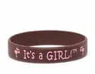 A brown bracelet with pink lettering and the words " it's a girl ".