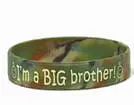 A green and brown camouflage wristband with the words " i 'm a big brother !" written on it.