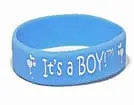 A blue bracelet with the words " it's a boy !" written on it.