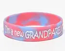 A pink and blue bracelet with the words " i 'm new grandparent ".